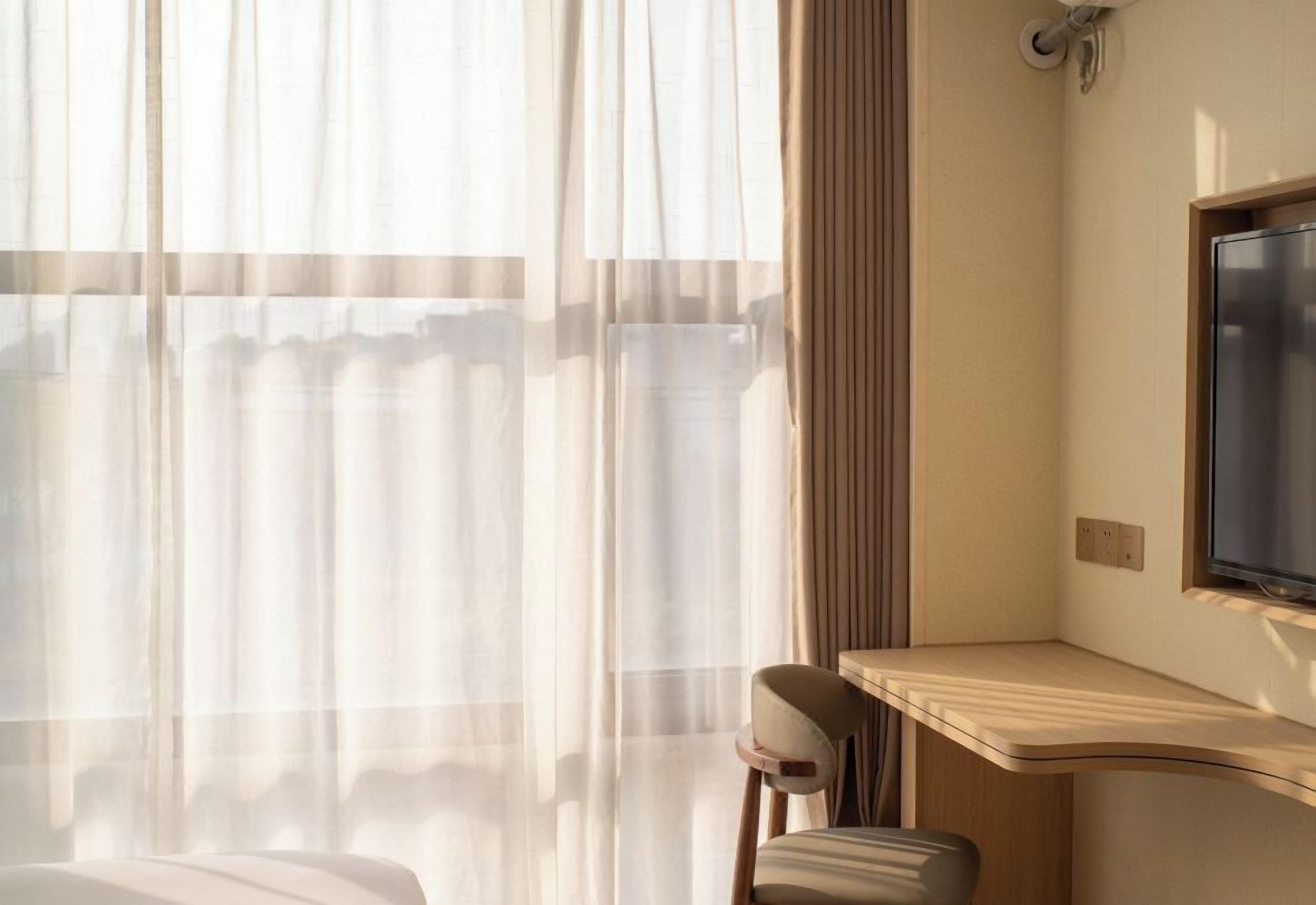 A hotel room with a bed, a desk, a chair, and a television.