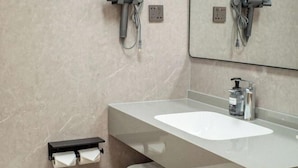 Un baño moderno con un espejo grande, un lavabo blanco, un perchero para toallas y un dispensador de jabón.