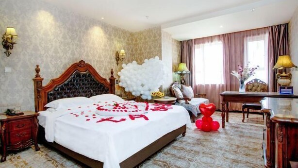 A hotel room with a large bed, a desk, and a chair. There are decorative items on the bed and a large white balloon decoration. - Tianjin International Hotel (Hotan City)