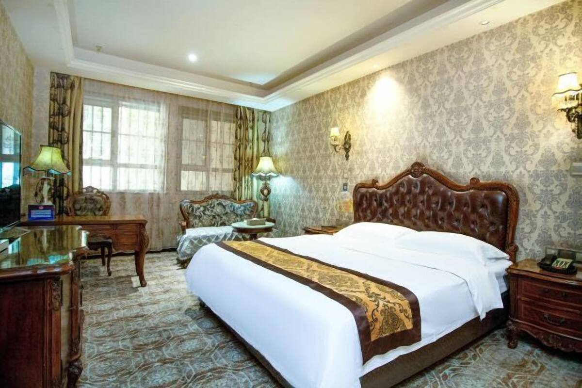 A hotel room with a large bed, a desk, a chair, and a TV.