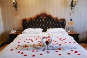 Una habitación de hotel con una cama grande, dos mesitas de noche y un cabecero de madera clásica.