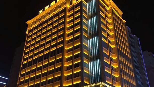 Un immeuble de grande hauteur dont les fenêtres, disposées en réseau, sont illuminées la nuit.