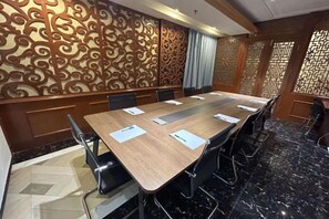 Une salle de conférence avec une longue table, des chaises et un panneau décoratif mural.
