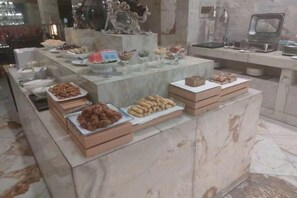 A buffet setup with various food items and a marble counter. - Tianjin International Hotel (Hotan City)