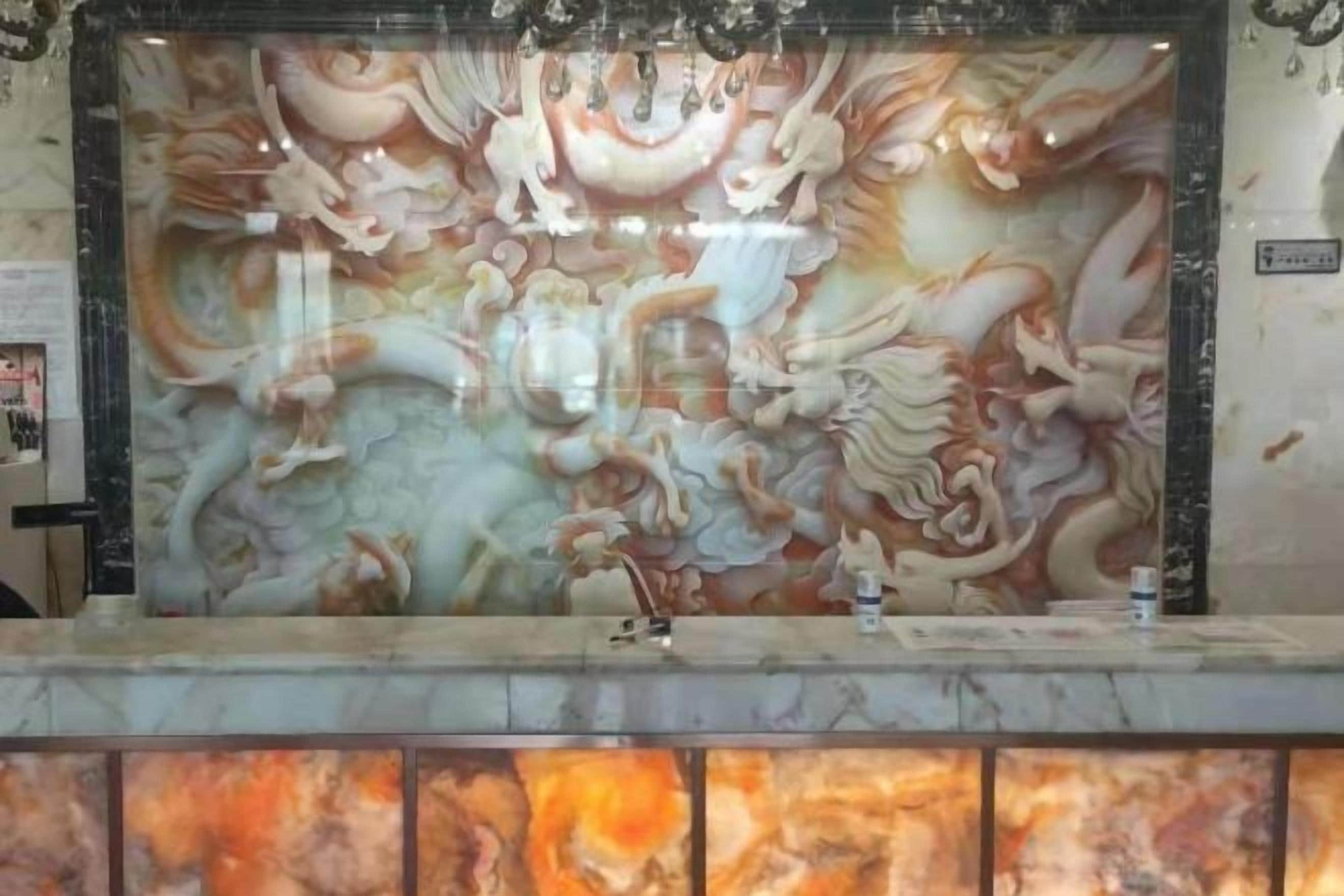 A reception area with a marble counter and a large, detailed mural on the wall.