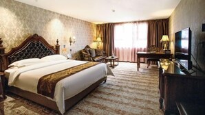 Une chambre d’hôtel avec un grand lit, un bureau, une chaise, une télévision et une lampe.