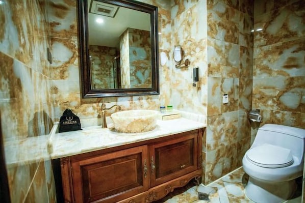 A bathroom with marble walls, a wooden vanity, a round sink, and a toilet. - Tianjin International Hotel (Hotan City)