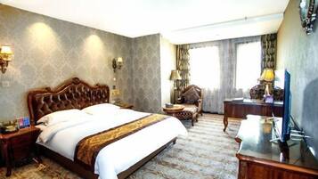 A hotel room with a large bed, a desk, a chair, a TV, and two lamps.