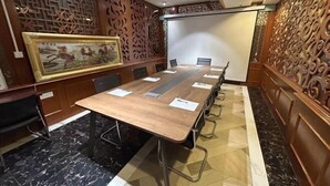 Une salle de conférence équipée d’une longue table, de chaises et d’un écran de projection.