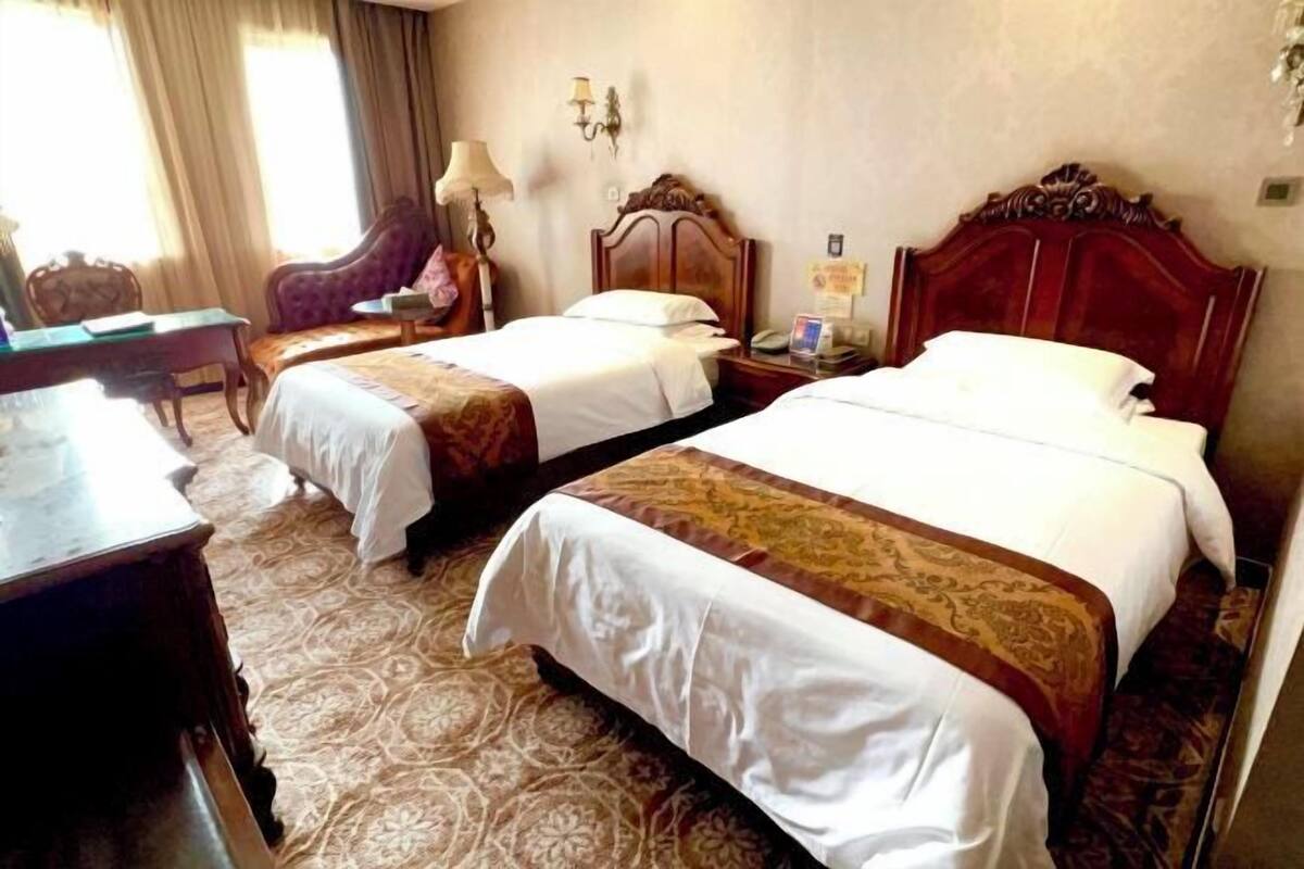 A hotel room with two beds, a desk, and a chair.