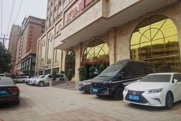 Un hôtel doté d’une entrée imposante, de plusieurs voitures garées et offrant une vue dégagée sur la façade du bâtiment.
