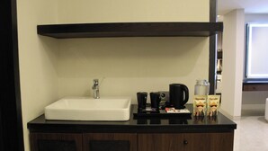 Un baño con lavamanos blanco, una cafetera y dos tazas de café sobre una bandeja.