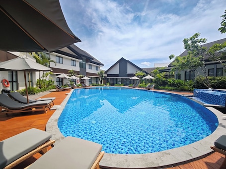 Una piscina al aire libre, sombrillas, sillones reclinables de piscina. Azana Garden Hill Resort Blora