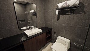 Un baño moderno con encimera negra, lavabo blanco, espejo, toallero y retrete.
