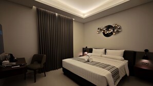 Una habitación de hotel moderna con una cama grande, un escritorio con una silla, una cafetera y un adorno en la pared.