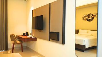 Habitación de hotel con escritorio, silla, cama y un espejo grande.