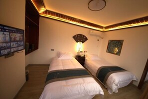 Une chambre d’hôtel avec deux lits, un téléviseur fixé au mur, une horloge et un élément décoratif mural.
