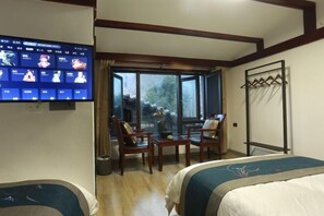 Une chambre d’hôtel avec deux lits, une télévision, une fenêtre donnant sur un beau paysage et un coin salon avec des chaises et une table.