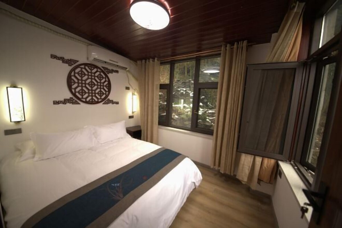 Une chambre d’hôtel avec un grand lit, un élément décoratif mural, une fenêtre avec des rideaux et un luminaire au plafond.