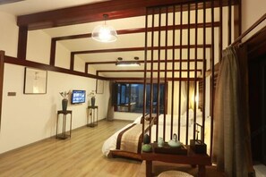 Une pièce de style japonais traditionnel, avec un sol recouvert de tatamis, un lit bas en bois, une porte coulissante et un téléviseur fixé au mur.