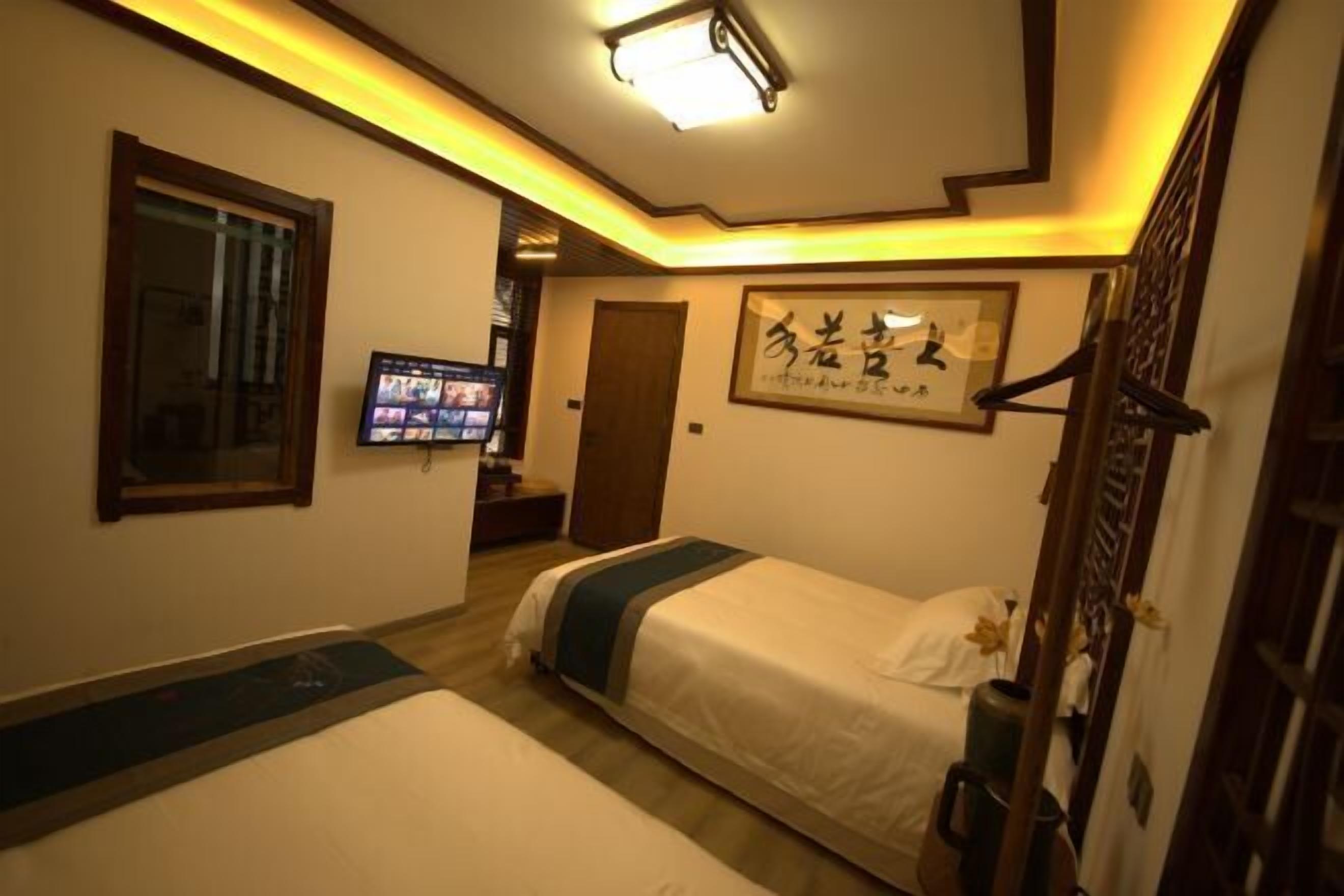 A hotel room with a bed, a television, a framed artwork, and a wooden door.