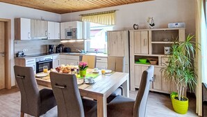 Cozinha moderna com armários de madeira, mesa de jantar com cadeiras e um vaso de planta.