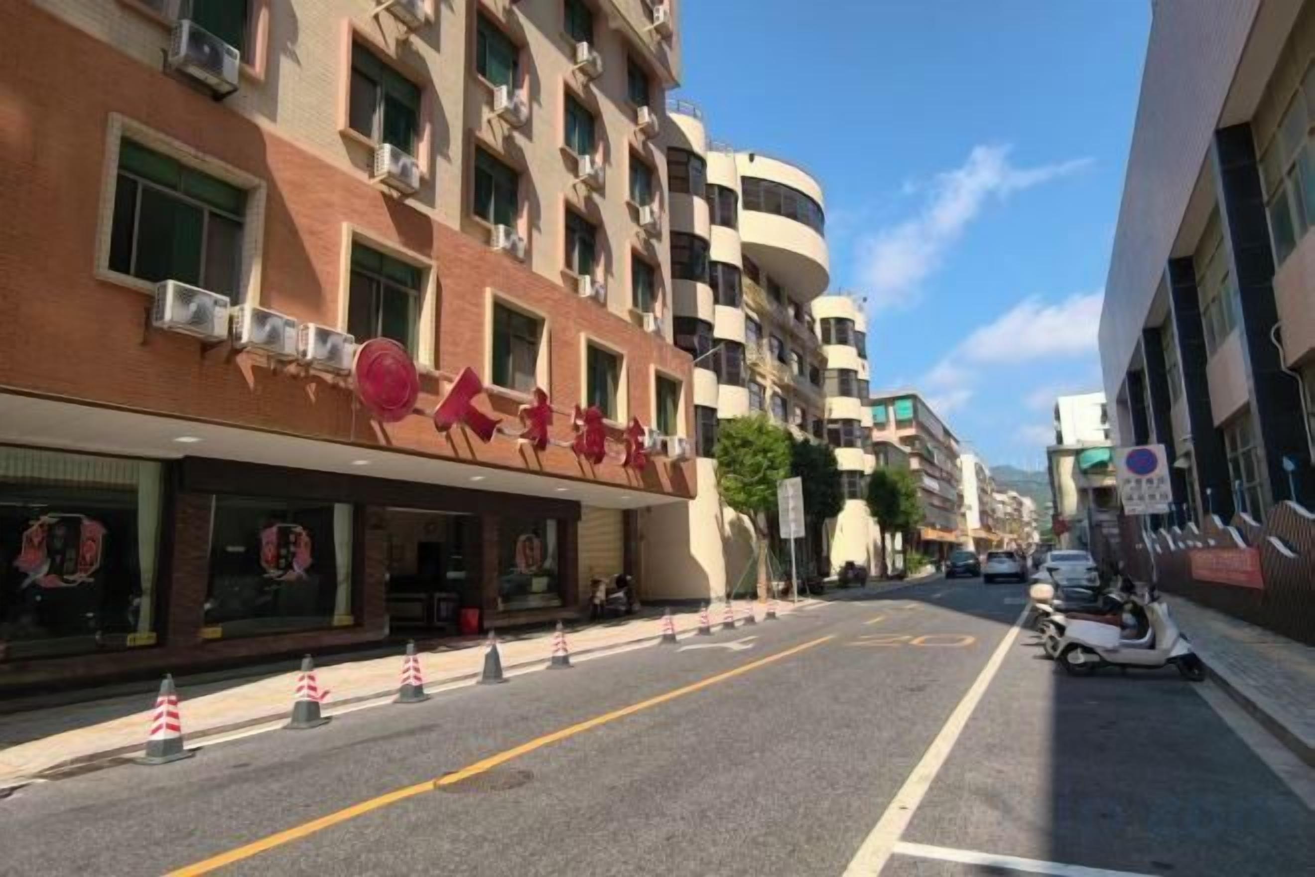 A street view with a building featuring a restaurant with a red awning and a sign.