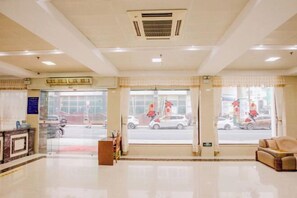 Welcome to our hotel lobby, featuring a reception desk, comfortable seating area, and large windows offering a view of the street.