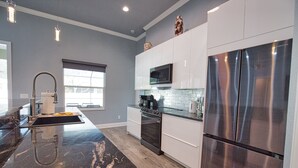 A modern kitchen with a stainless steel refrigerator, a microwave, and a stove. - 7 min to the Beach. Family Venice Beach Retreat. Private Saltwater Screened Pool (Venice)