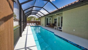 A covered outdoor swimming pool with a clear roof, a patio area with chairs, and a view of the surrounding landscape. - 7 min to the Beach. Family Venice Beach Retreat. Private Saltwater Screened Pool (Venice)
