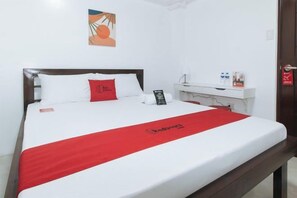 Une chambre d’hôtel avec un lit, une table de chevet avec un téléphone, un oreiller rouge et une couverture rouge.