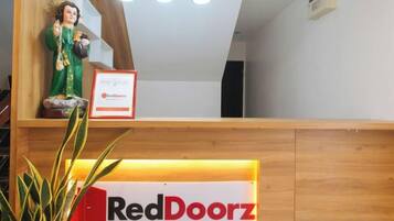 Uma receção com o letreiro RedDoorz, uma estátua e uma planta.