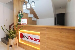 A reception desk with a RedDoorz sign, a statue, and a staircase. - RedDoorz near UST Sampaloc Manila (City of Manila)