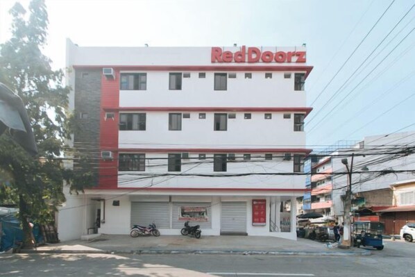 Un edificio de varios pisos con fachada roja y blanca, entrada de garaje visible y un letrero que dice 'Red Doors'.