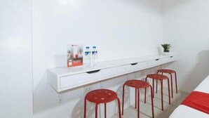 A white wall with a white console table, three red stools, and a small potted plant. - RedDoorz near UST Sampaloc Manila (City of Manila)