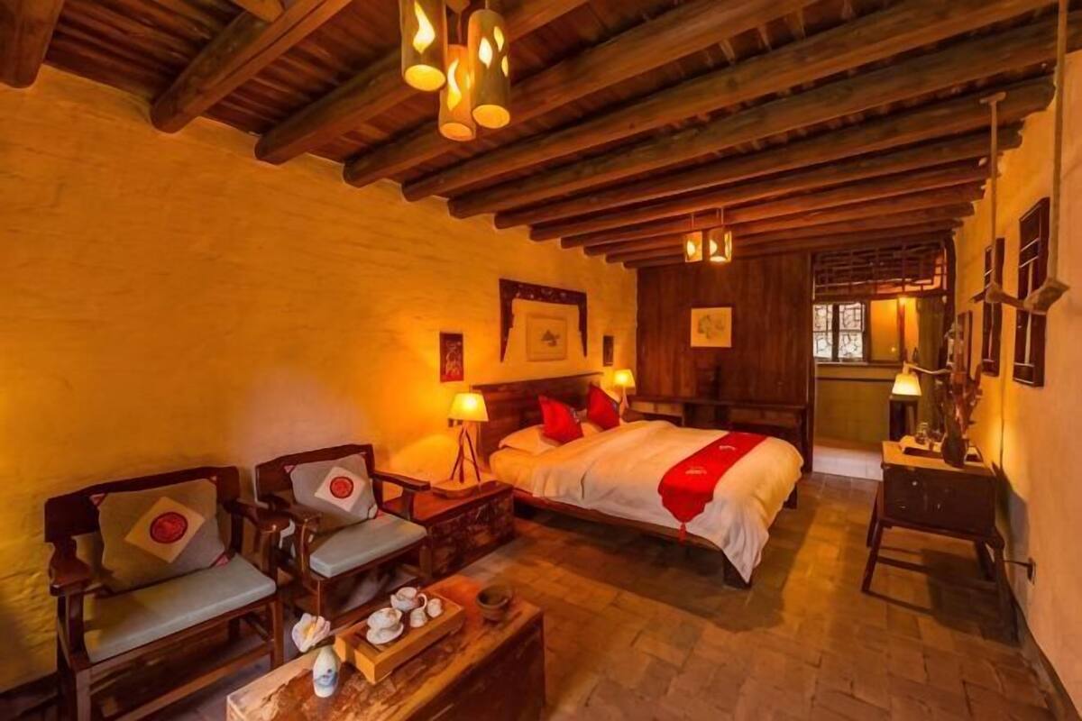 A traditional room with a bed, two chairs, a small table, and a wooden ceiling.