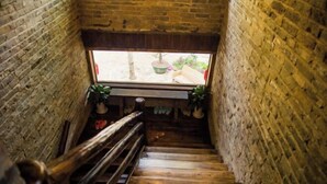 A wooden staircase in a rustic brick building with a window at the top. - Yangshuo Countryside Washe Inn (Yulonghe Scenic Area) (Yangshuo)
