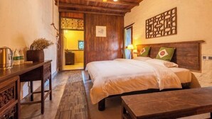 A cozy room with a wooden ceiling, a bed with white linens, a wooden desk with a kettle, and a small table. - Yangshuo Countryside Washe Inn (Yulonghe Scenic Area) (Yangshuo)