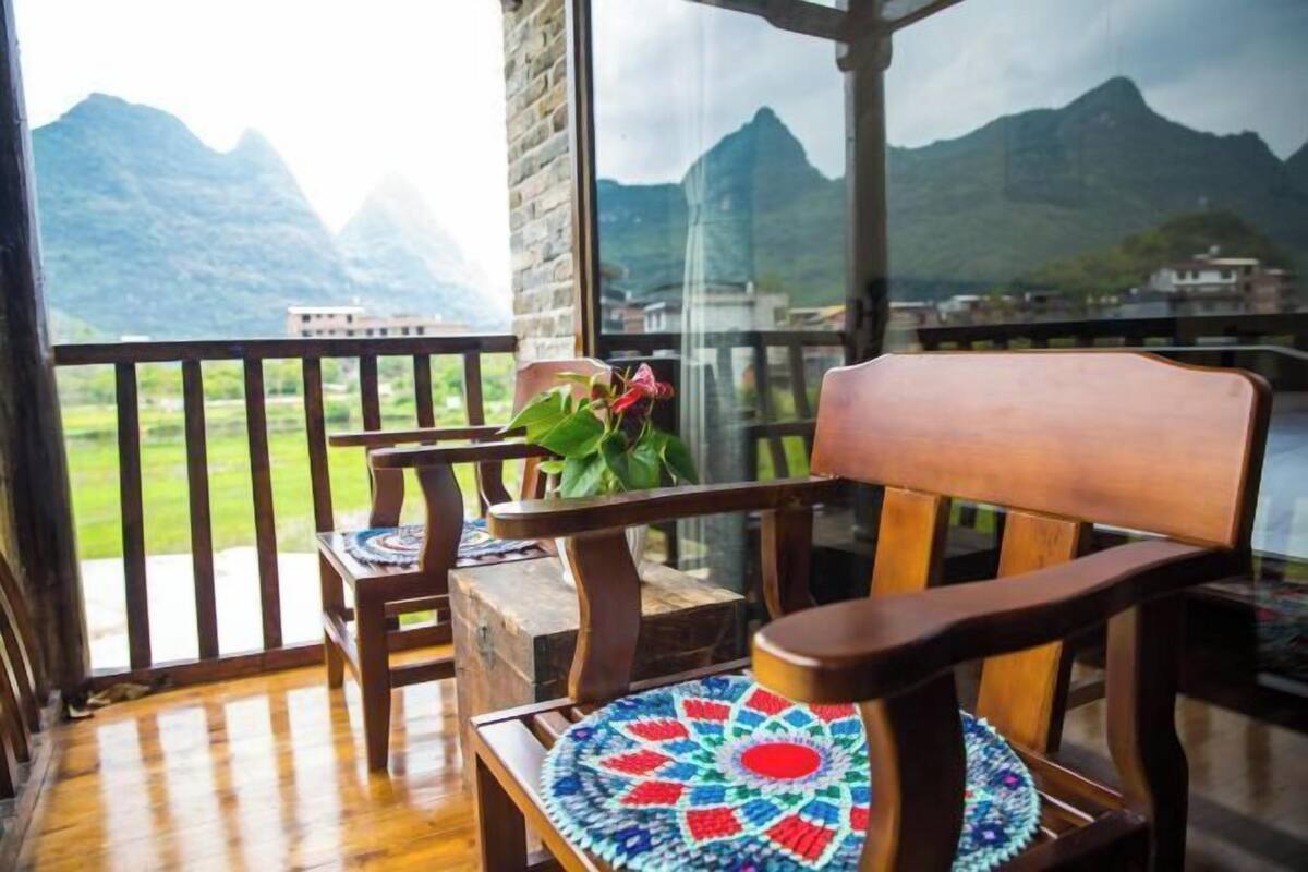 A balcony with a wooden chair and a table, overlooking a mountainous landscape.