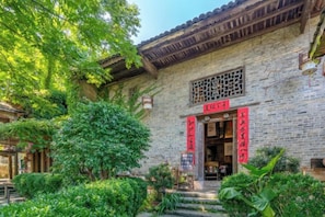 A traditional building with a tiled roof, a wooden door, and a red sign above the entrance. - Yangshuo Countryside Washe Inn (Yulonghe Scenic Area) (Yangshuo)