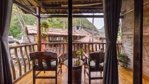 A wooden balcony with a view of traditional houses and greenery. - Yangshuo Countryside Washe Inn (Yulonghe Scenic Area) (Yangshuo)