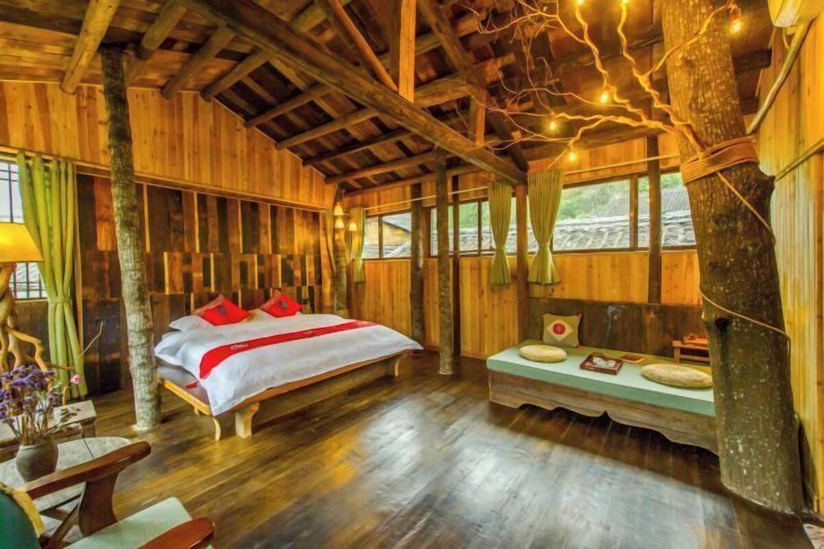 A wooden cabin-style room with a bed, a bench, and a window.
