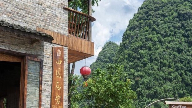 A rustic building with a balcony, a wooden sign, and a red lantern. - Yangshuo Countryside Washe Inn (Yulonghe Scenic Area) (Yangshuo)