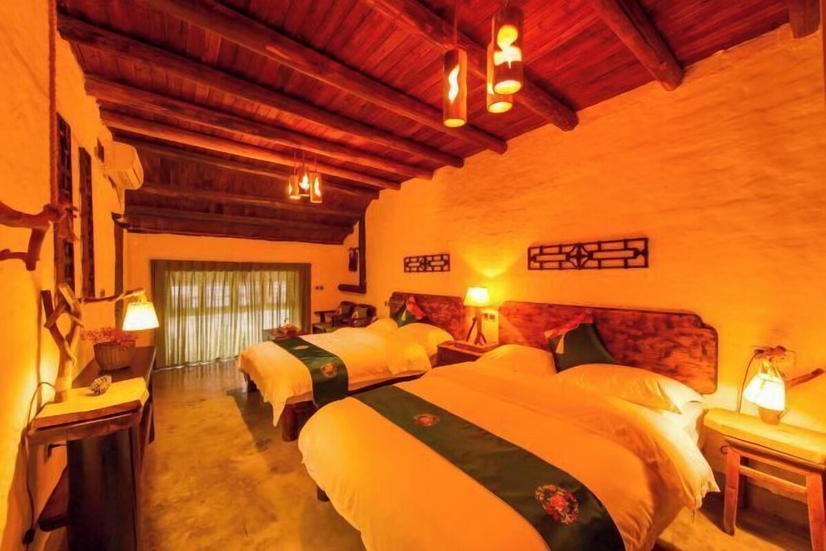 Ein Hotelzimmer mit drei Betten, Holzbalken an der Decke und einer gemütlichen Atmosphäre.