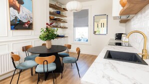 Une cuisine moderne dotée d’un plan de travail en marbre, de meubles en bois et d’un évier noir.