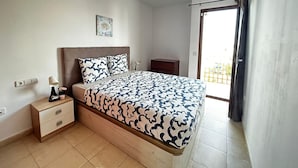 A bedroom with a bed, bedside table, lamp, and a small cabinet. There is a window with a view of the outside. - House - Sleeps 4 & Swimming Pool (Tias)