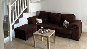 A living room with a brown sectional sofa, a small wooden table, and a staircase. - House - Sleeps 4 & Swimming Pool (Tias)