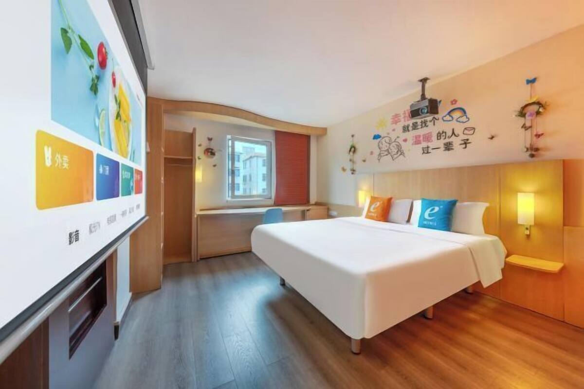 A hotel room with a bed, a desk, and a window.