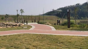 A paved pathway leading to a building with a signboard, surrounded by grass and trees. - Dongguan Qingxi E Hotel (Dongguan)