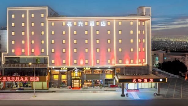 A hotel with multiple floors, a prominent entrance with a covered area, and illuminated signage. - Dongguan Qingxi E Hotel (Dongguan)